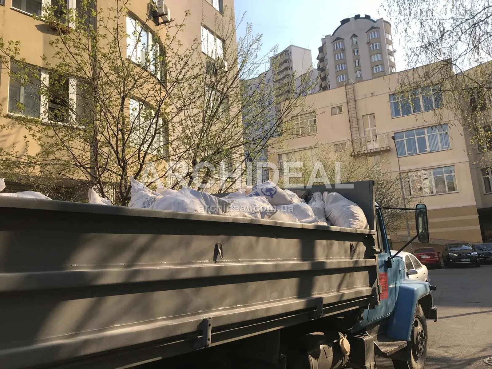 Вантажівка з мішками сміття у дворі багатоповерхівки