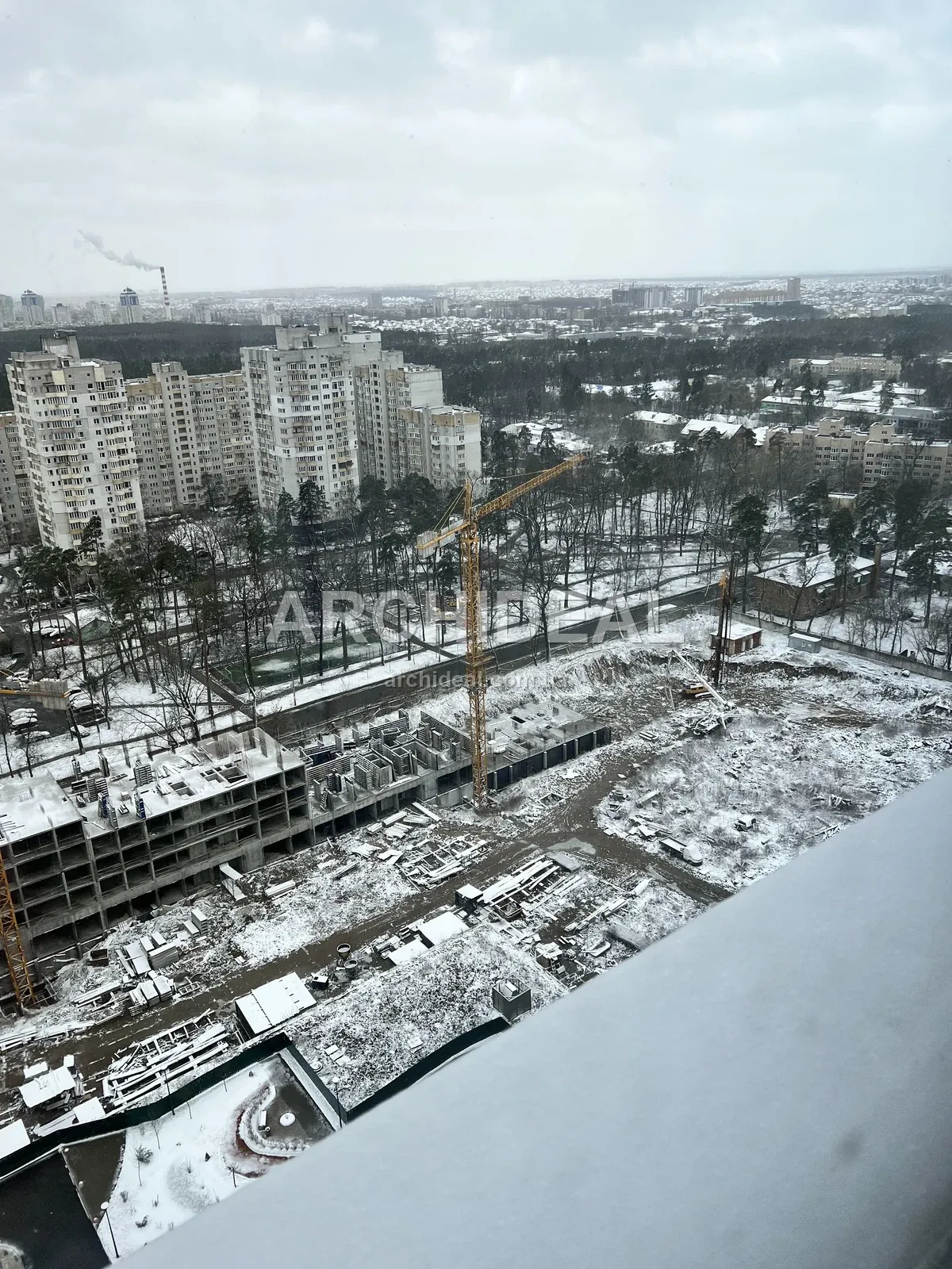 Зимовий будівельний майданчик з висоти, штабелі конструкцій